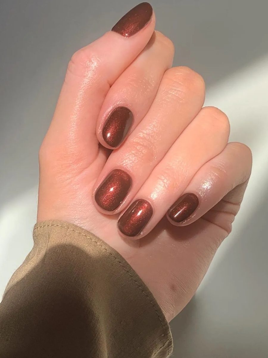 Short oval nails in warm chocolate brown with copper shimmer