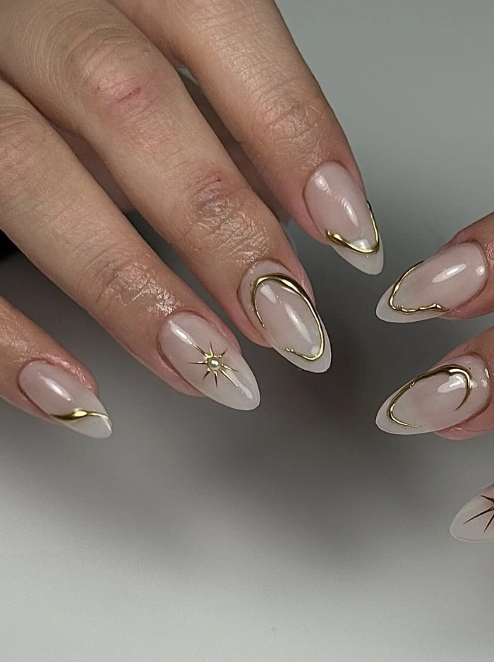 Stiletto nails with celestial gold outline art along the tips