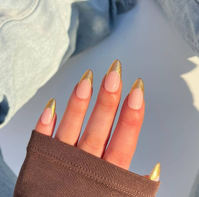 Almond nails with gold French tips on a nude base