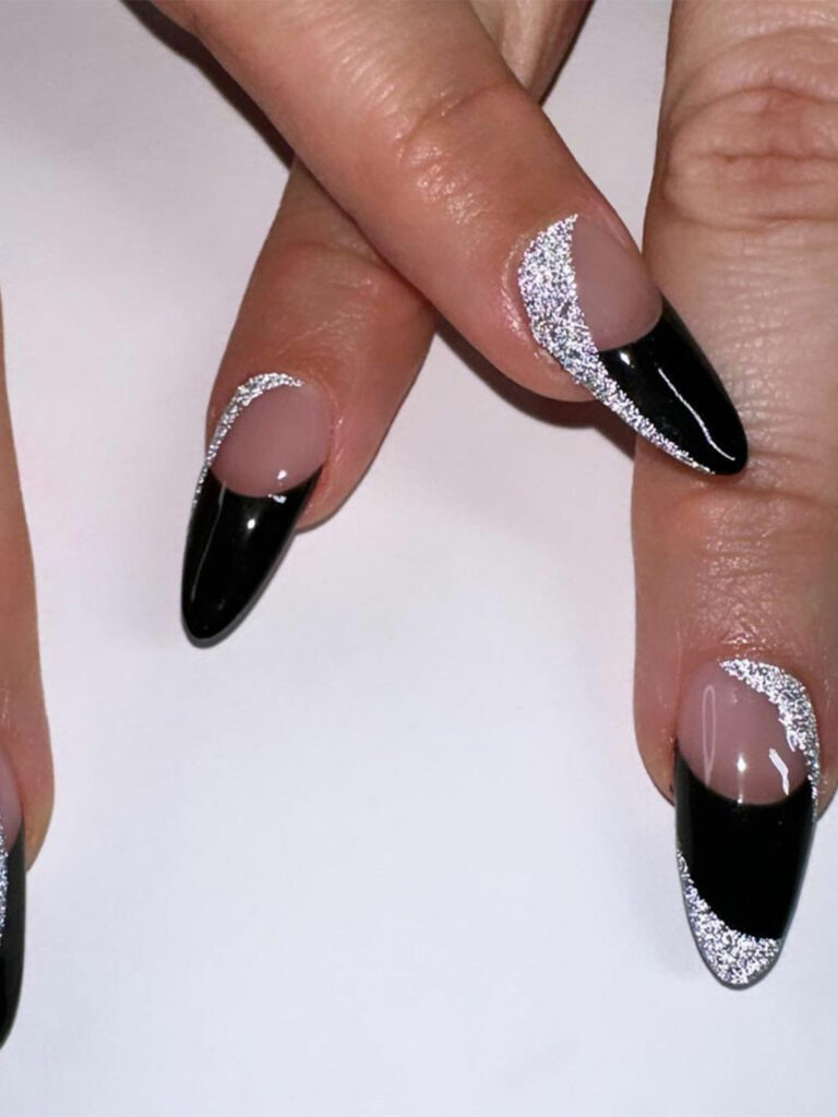 Nude almond nails with black French tips edged in silver glitter