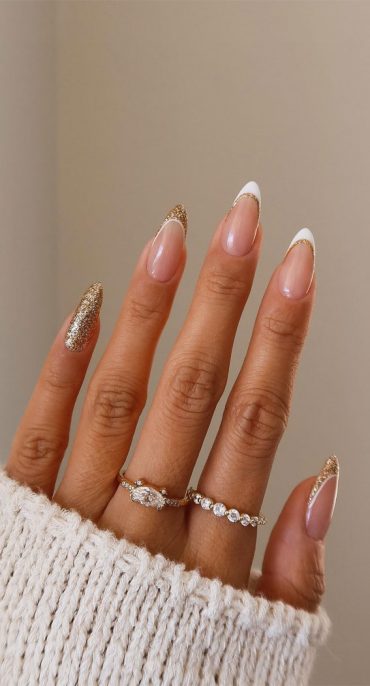 Long almond nails with white French tips edged in gold glitter and one full gold glitter accent nail