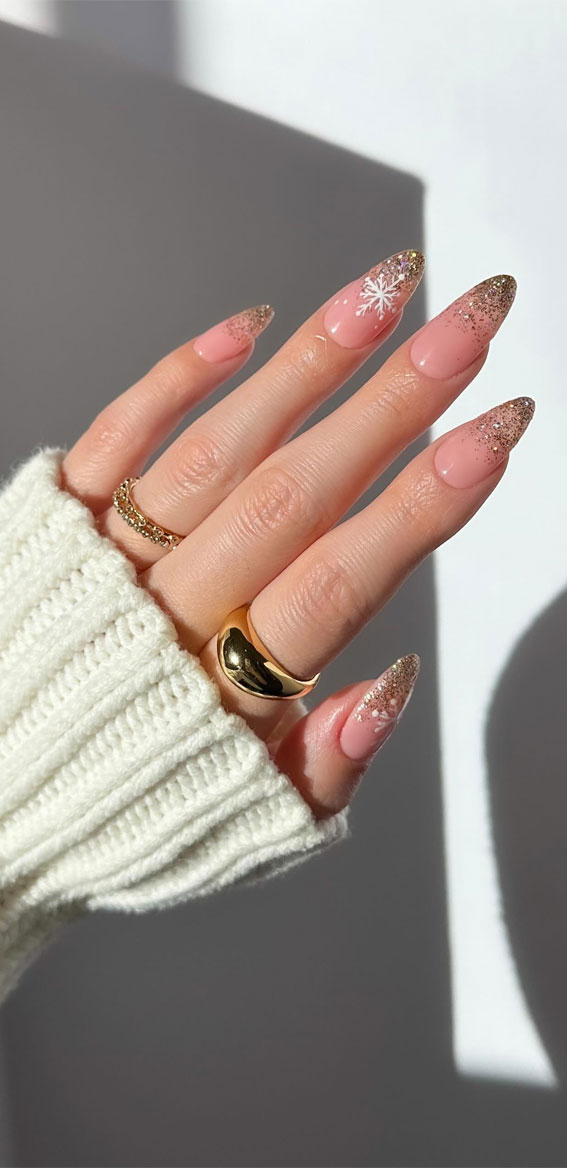 Blush pink almond gel nails with gold glitter tips and a white snowflake accent