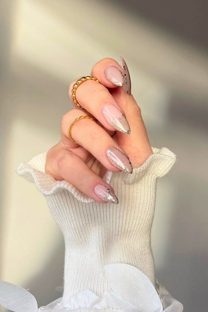 Long nude stiletto nails with silver glitter fading up from the tips
