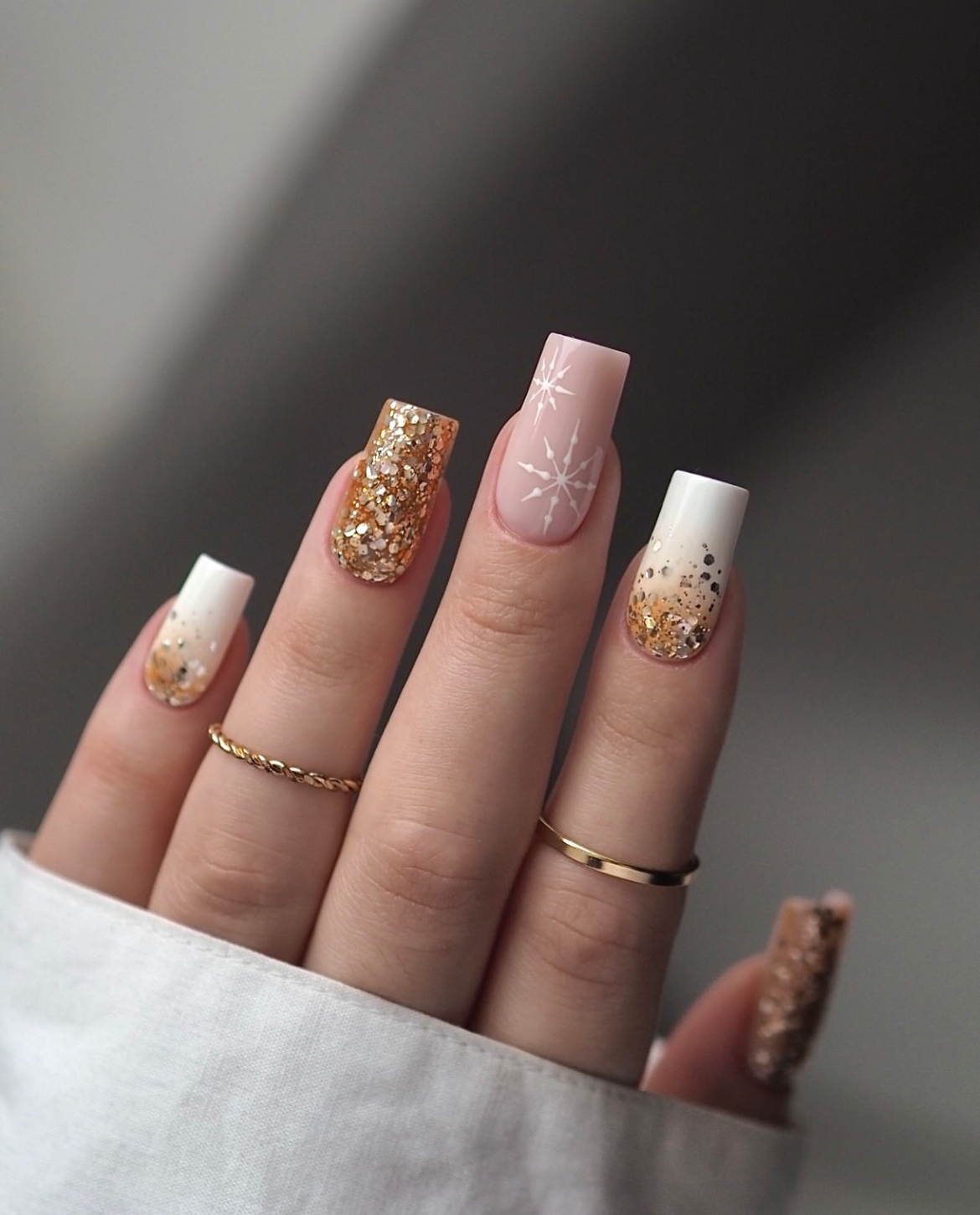 Long square nails in a mix of white, gold glitter, and snowflake art