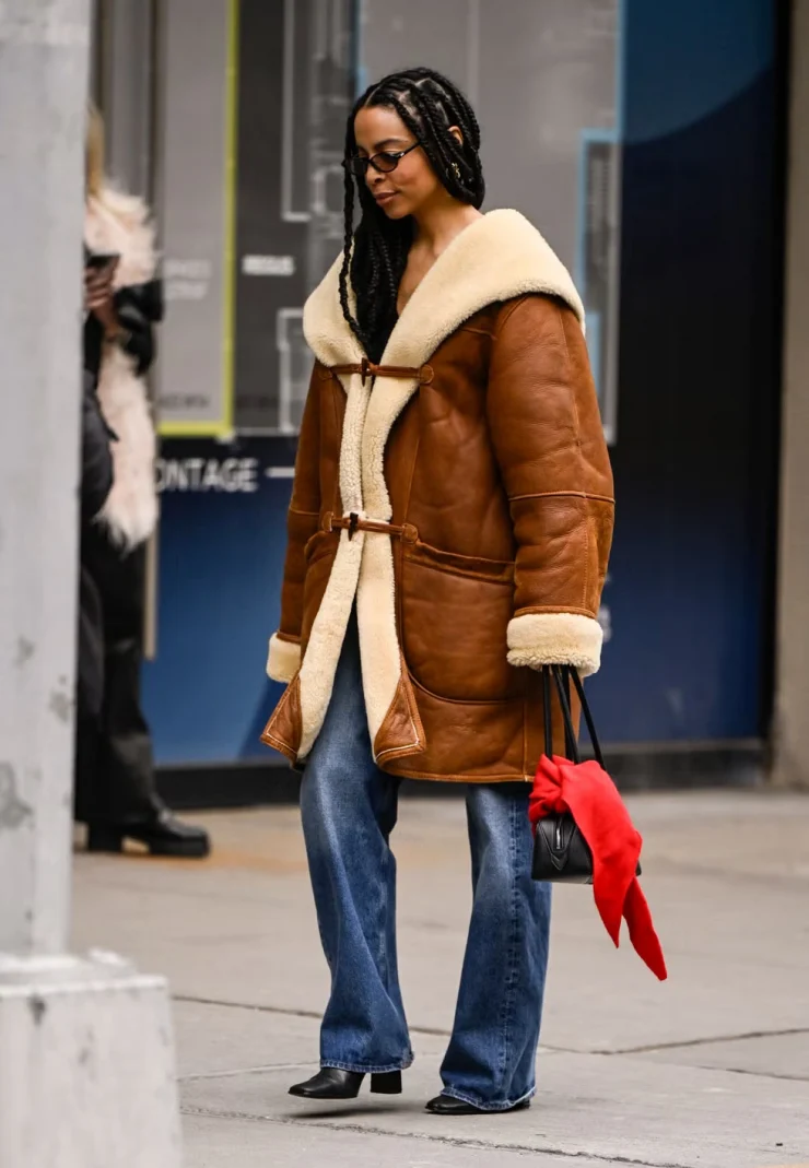 Woman wearing a caramel shearling toggle coat with wide-leg jeans on a New York street