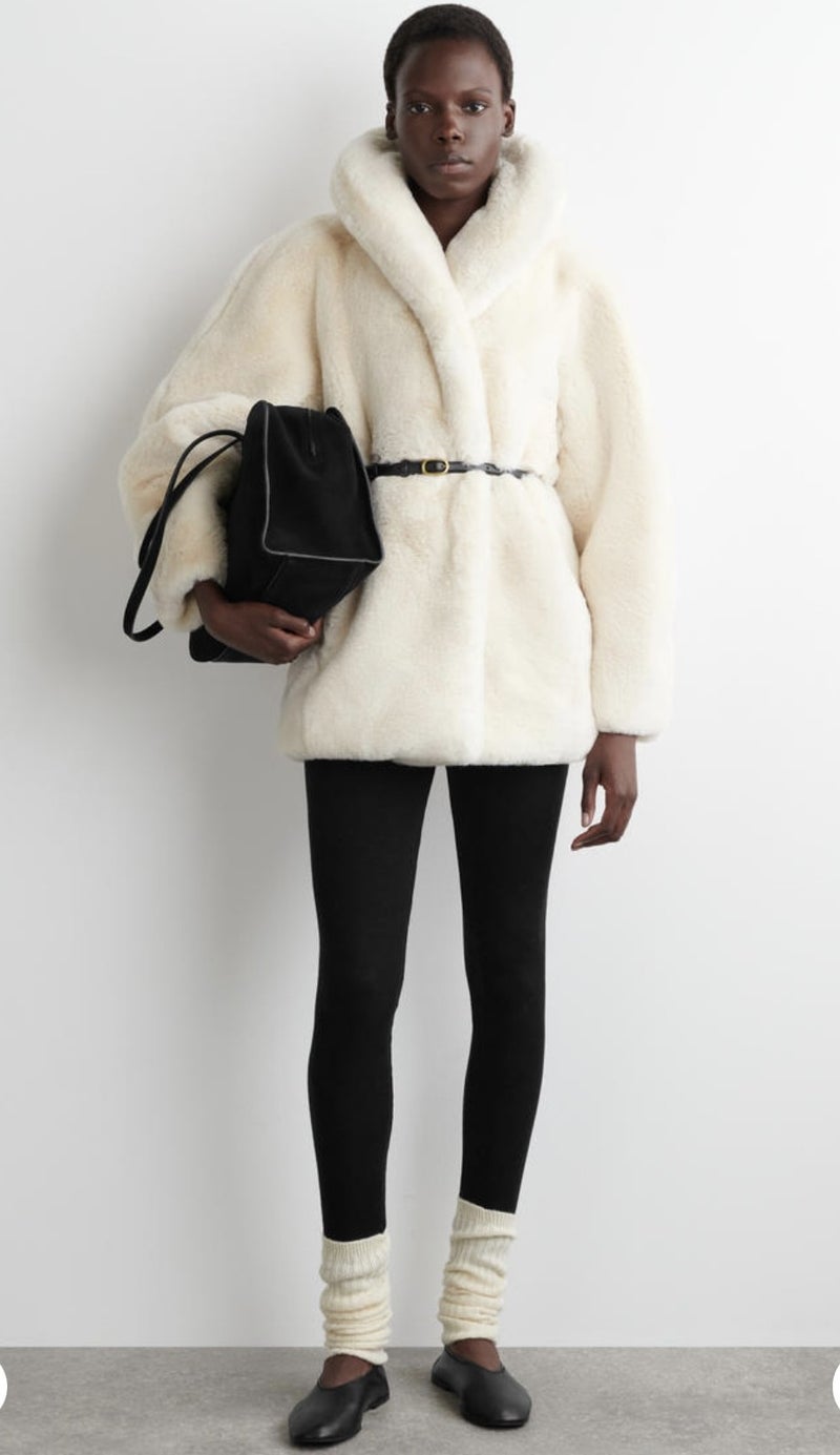 Oversized cream faux fur coat with black leggings and cream leg warmers