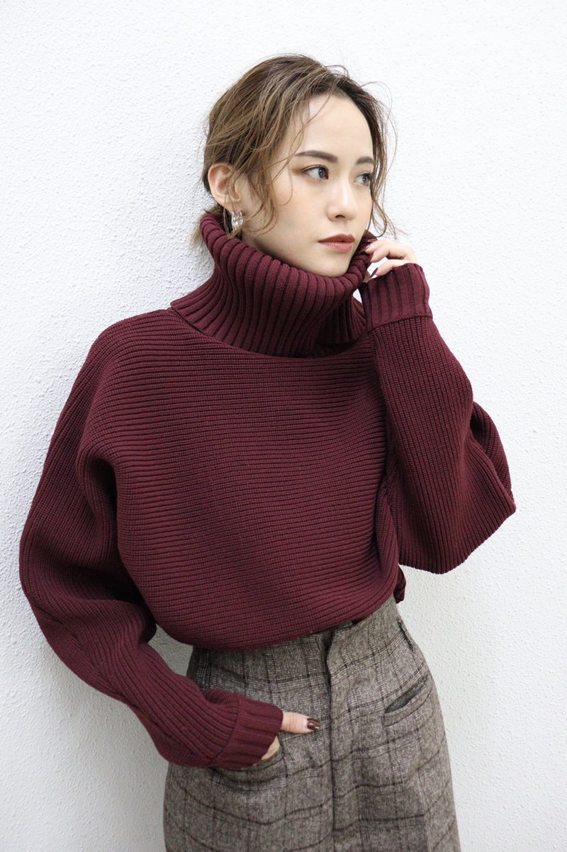 Woman wearing a burgundy chunky ribbed turtleneck sweater with grey plaid wide-leg trousers