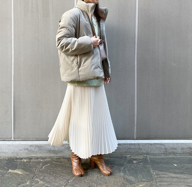 Greige puffer jacket with a cream pleated midi skirt and tan heeled ankle boots