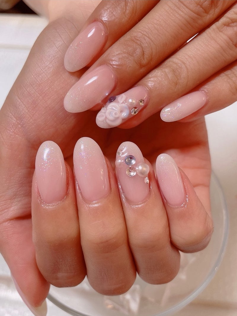 Medium almond nails in soft blush pink with pearl, flower and rhinestone clusters on accent nails