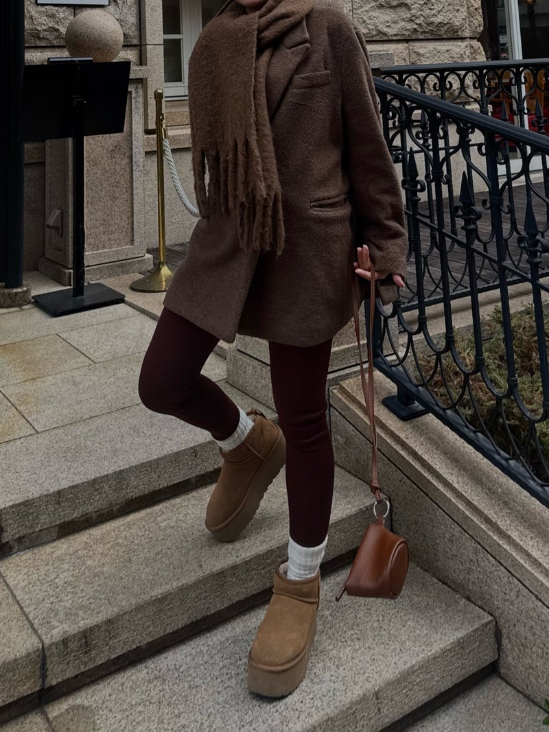 Woman in a brown wool coat and burgundy leggings wearing chestnut platform mini ugg boots with white socks