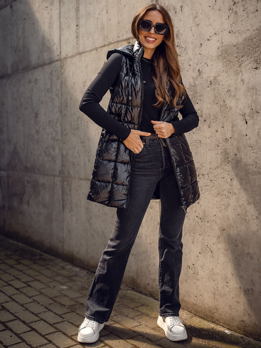 Woman wearing a black quilted puffer vest over a black ribbed top with black jeans and white platform sneakers