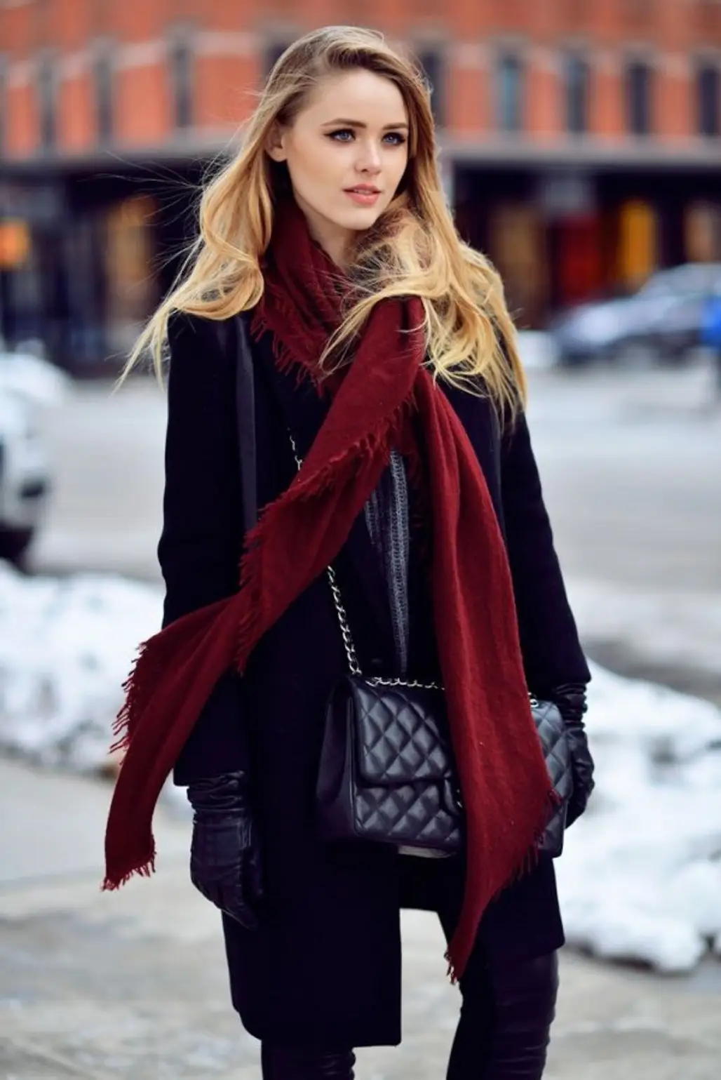 Long black wool coat with a long burgundy fringed scarf and quilted black bag