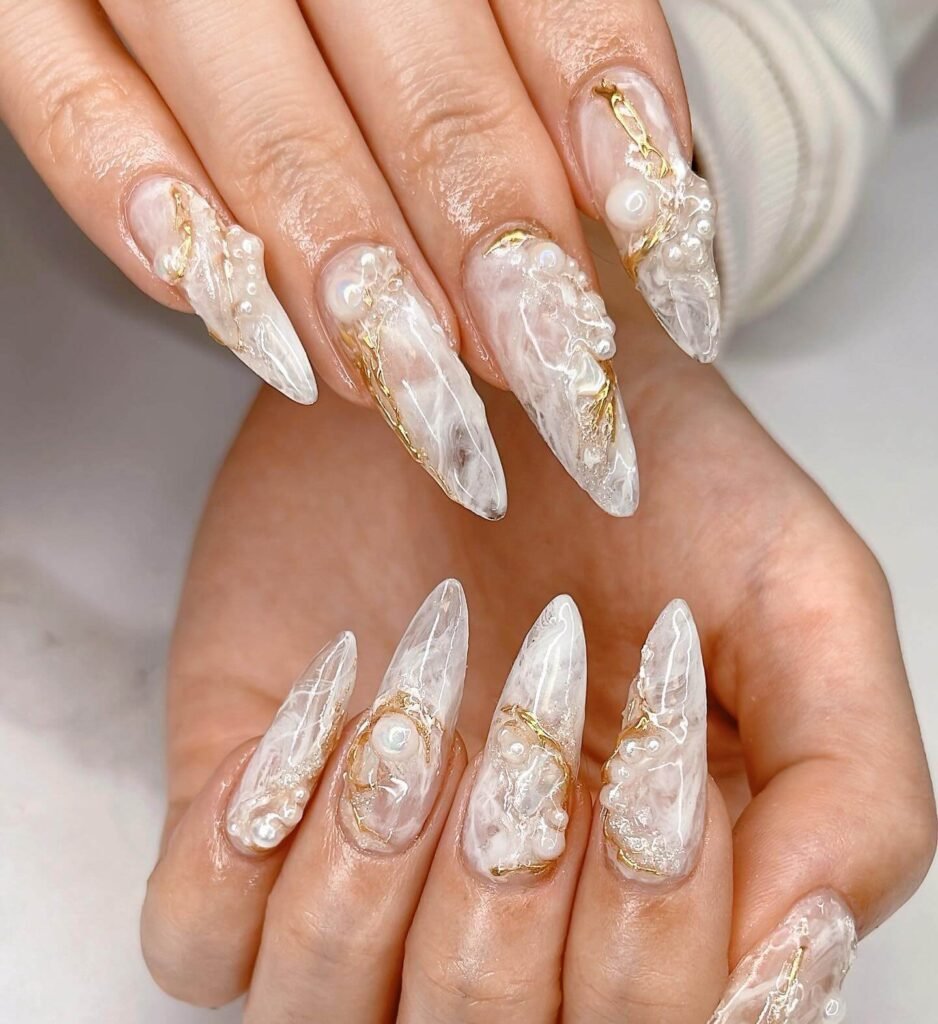 Long stiletto translucent nails with 3D pearls and gold foil accents