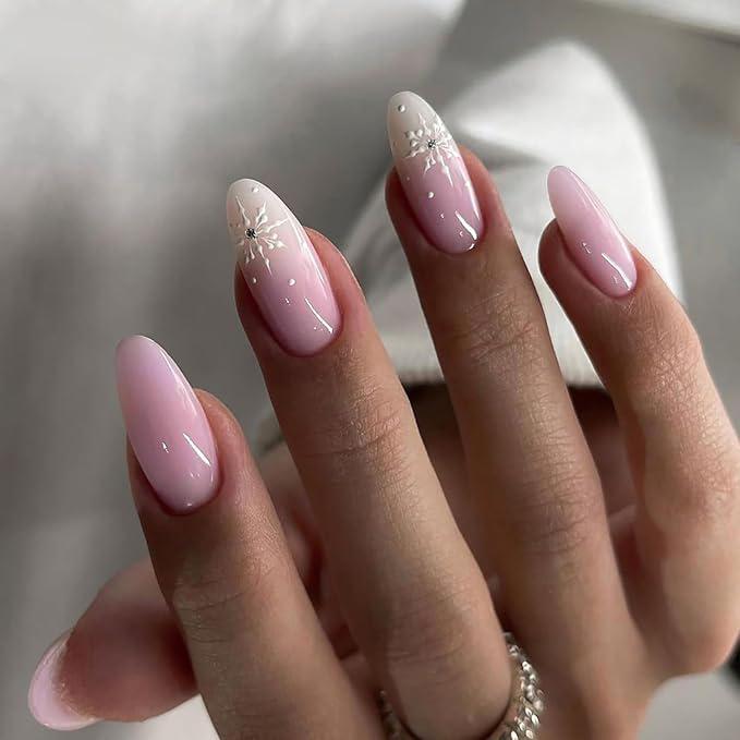 Pink almond nails with white snowflake nail art and small gems