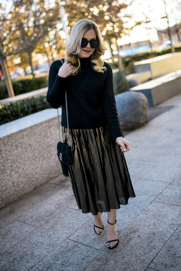 Woman wearing a gold pleated skirt styled for a New Year's Eve outfit