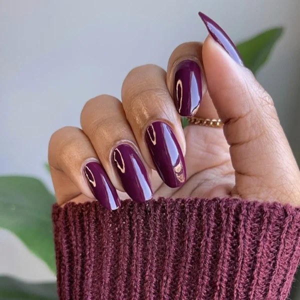 Medium almond nails in a glossy deep plum polish with a mirror-shine finish