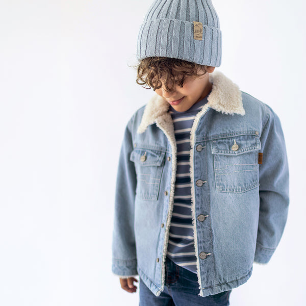 A child wearing a sherpa-lined winter jacket with a beanie