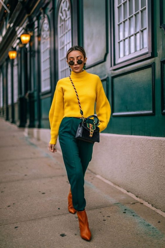 Woman in a mustard turtleneck sweater, green trousers and tan ankle boots