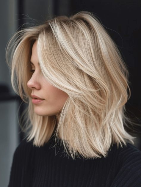 Woman with a platinum blonde layered lob haircut and darker shadow root