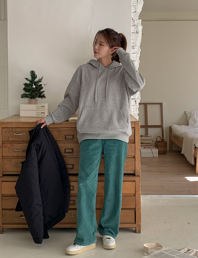 Woman in grey hoodie, teal corduroy wide-leg pants and white sneakers