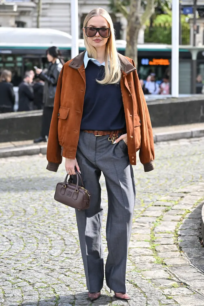 Woman in a rust suede jacket with a navy sweater and grey wide-leg trousers