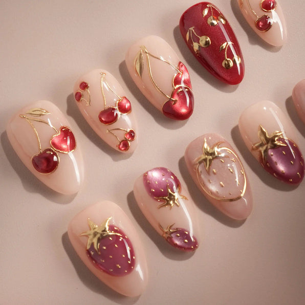 Press-on nails with gold-outlined cherry and strawberry art