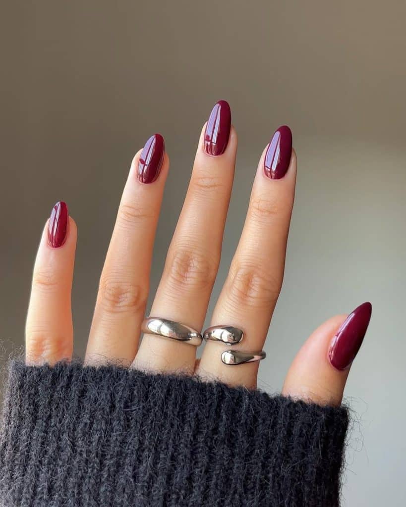 Almond nails in a classic glossy wine-red crème polish; real photography.