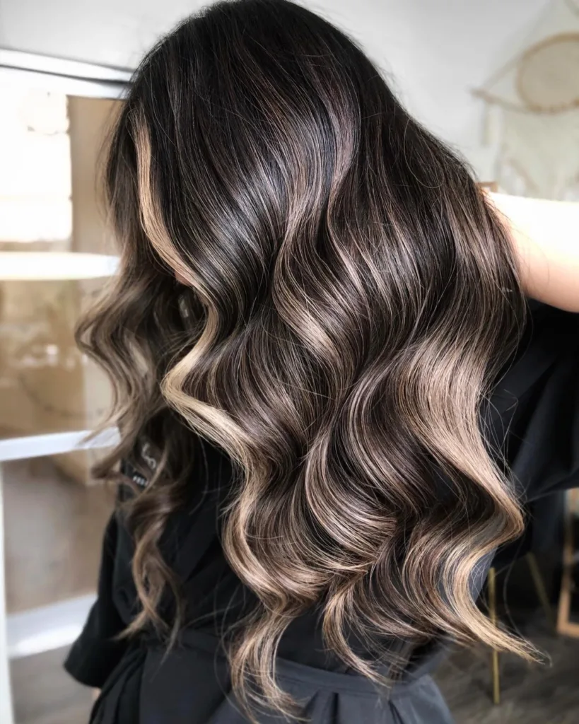 Back view of long wavy dark hair with ash beige blonde balayage ends