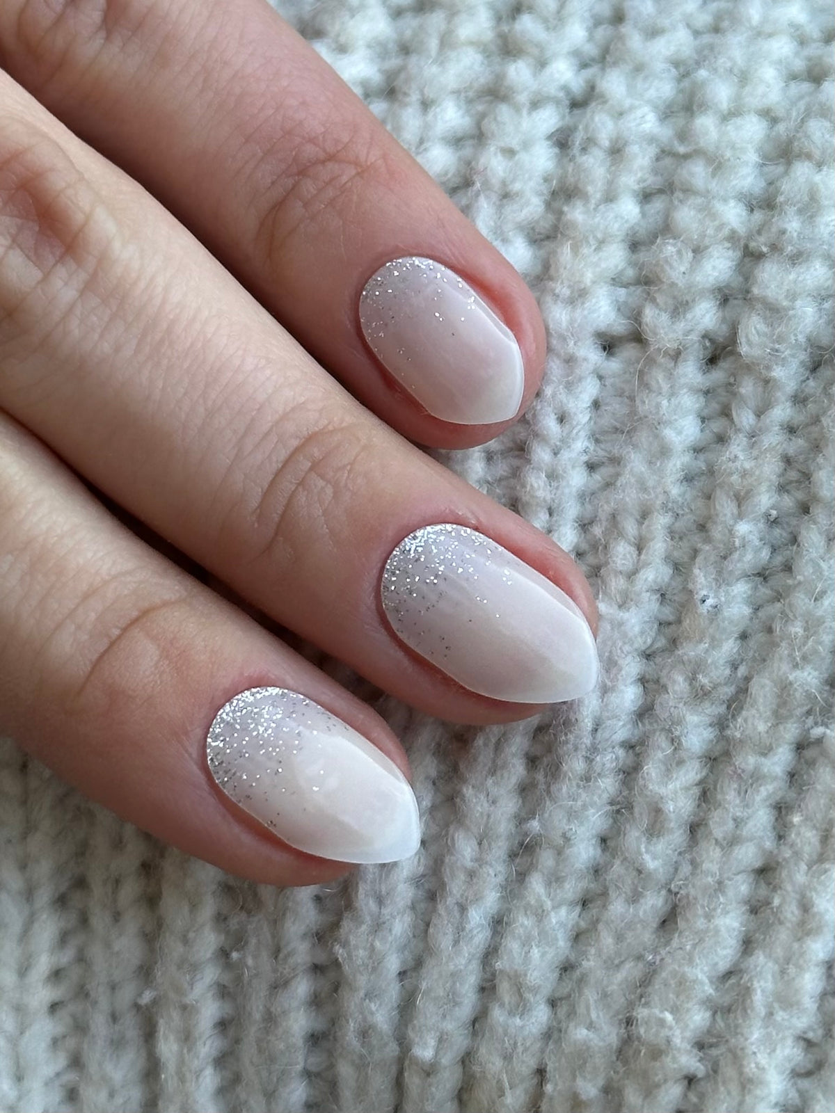 Milky white gel nails with a silver glitter fade near the cuticles
