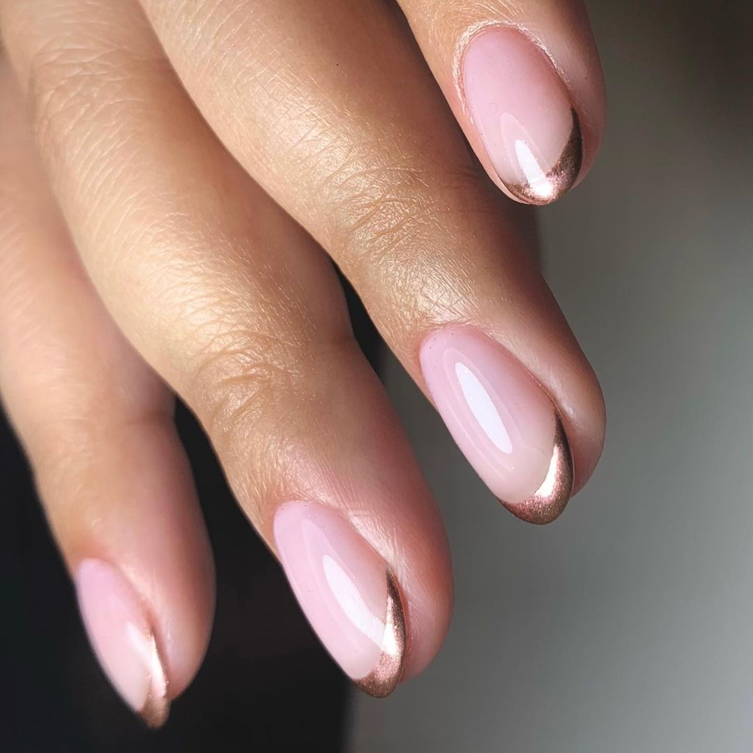 Nails with rose gold metallic French tips over a nude base