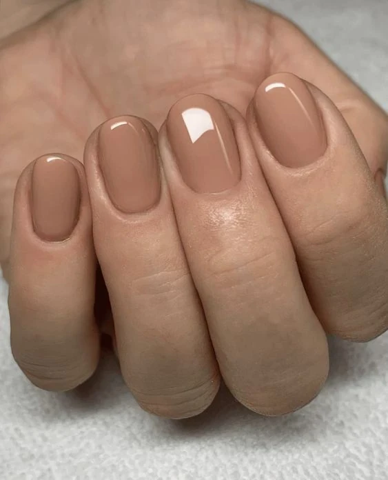 Short almond-shaped nails in a creamy beige nude polish