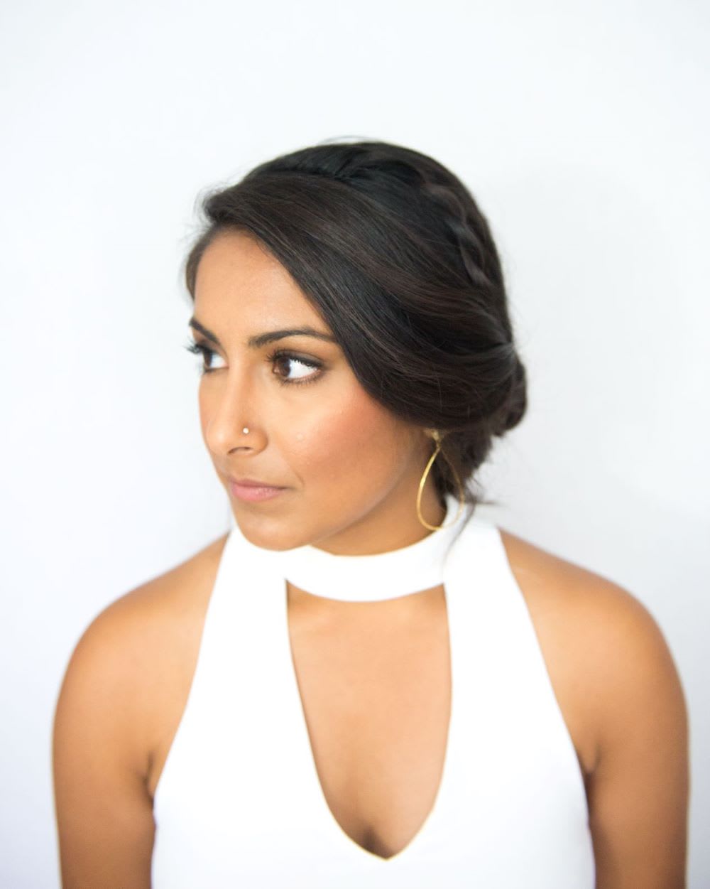 Three-quarter view of a twisted low knot bun with a side-swept face-framing bangs section.