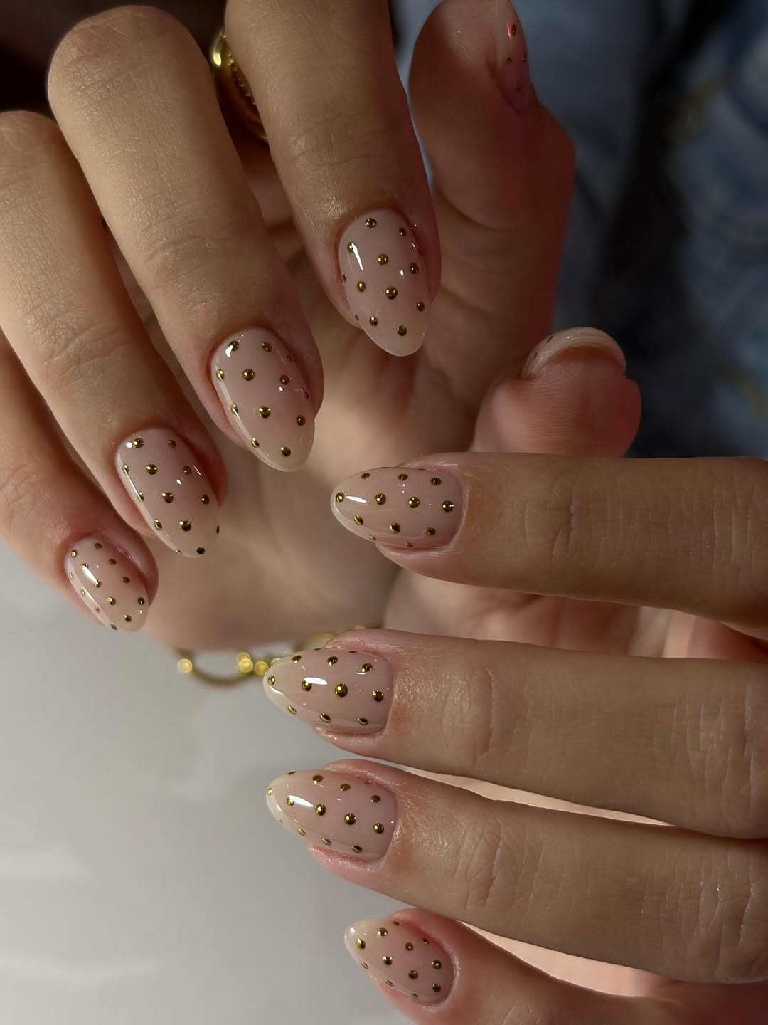 Oval nails in sheer nude with tiny gold polka dot accents