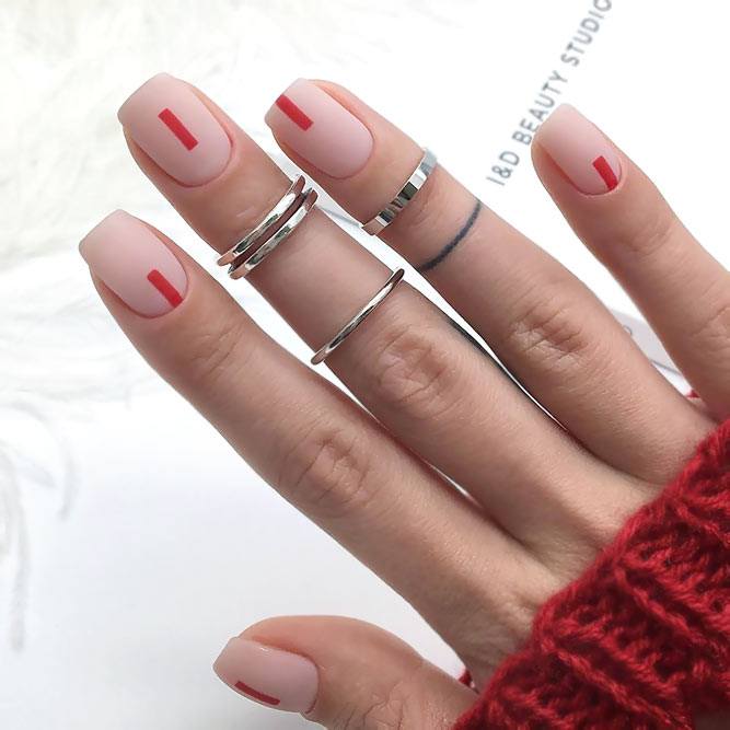 Nude matte nails each with a single thin hand-painted red vertical stripe.