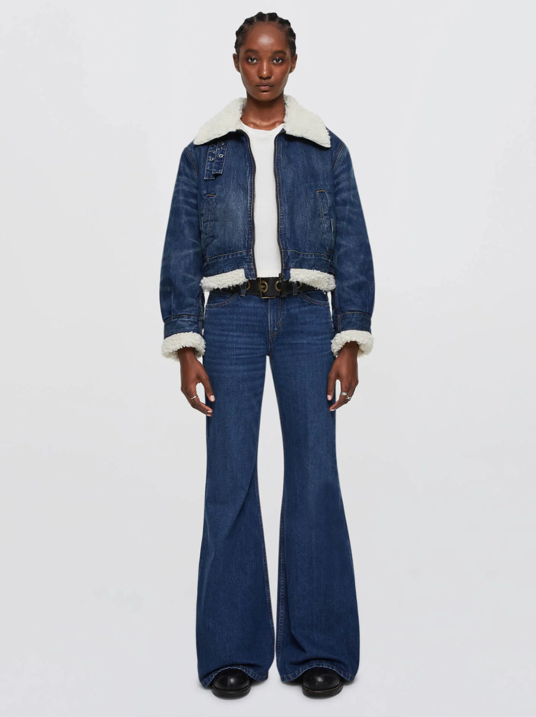 Woman in a sherpa-lined cropped denim trucker jacket with dark bootcut jeans and black boots
