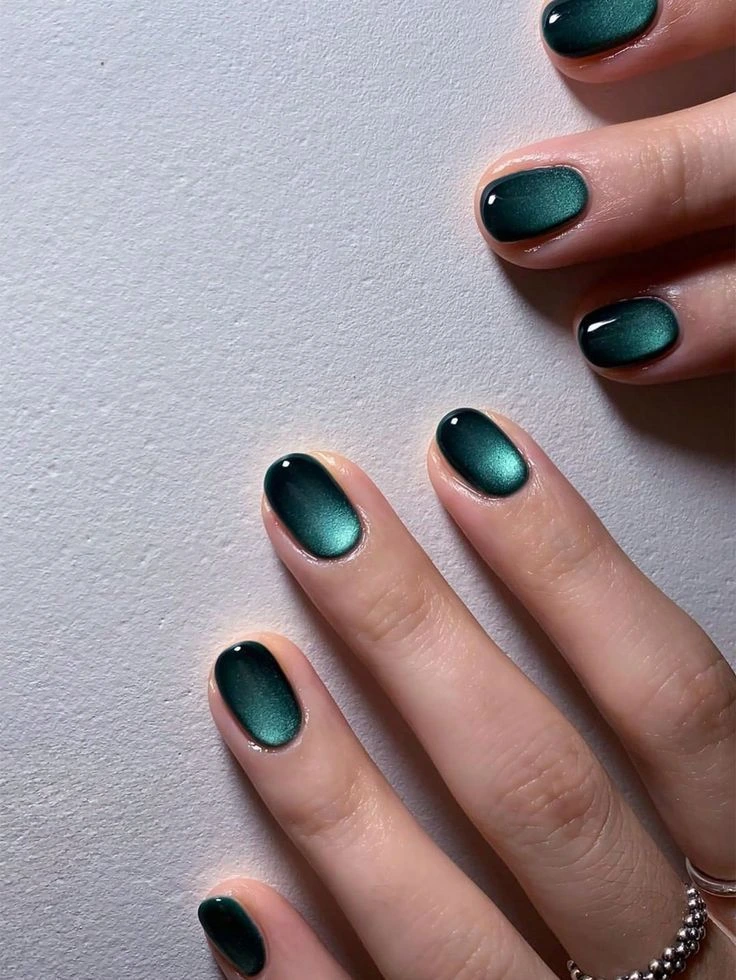Short oval nails in deep teal green velvet cat-eye finish