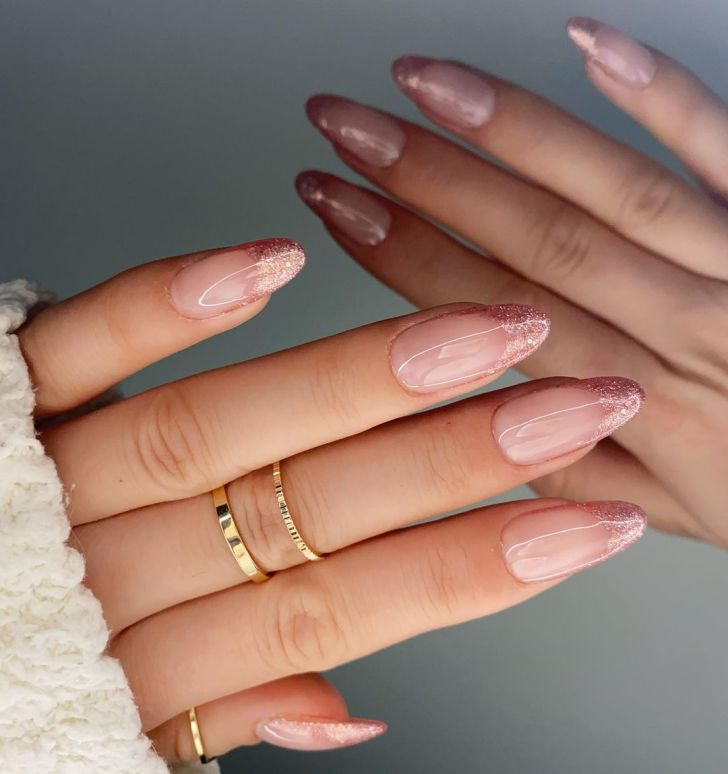 Almond nails with rose gold glitter French tips over a nude base