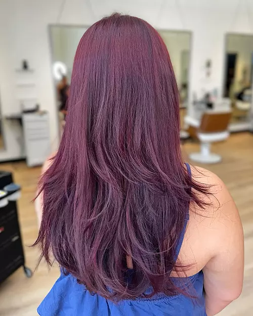 Back view of medium-length vivid cherry cola hair with feathered layers