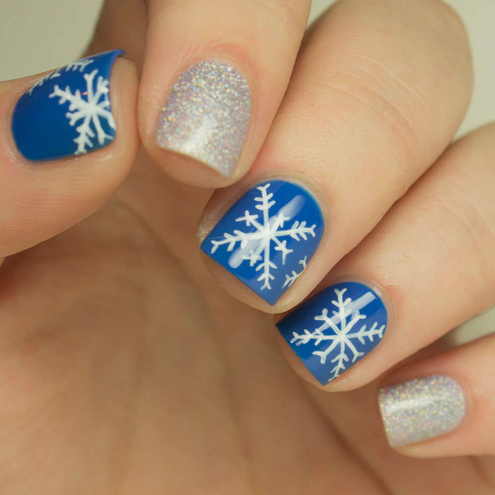 Short cobalt blue Christmas nails with white snowflakes and silver glitter
