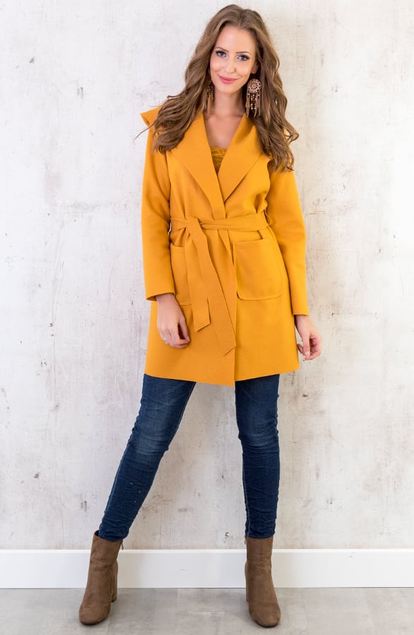 Woman wearing a mustard yellow belted wool coat with dark skinny jeans and brown ankle boots