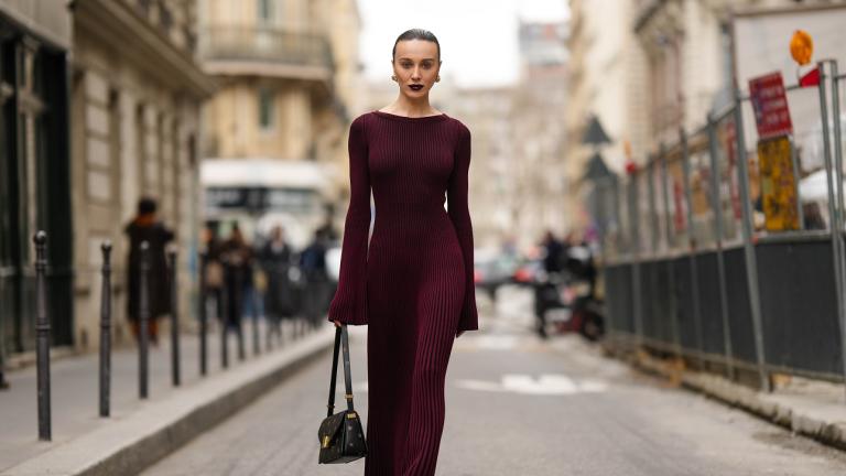 Woman in a burgundy ribbed knit midi dress with bell sleeves on a city street