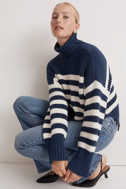 Woman wearing a striped turtleneck sweater with dark denim jeans
