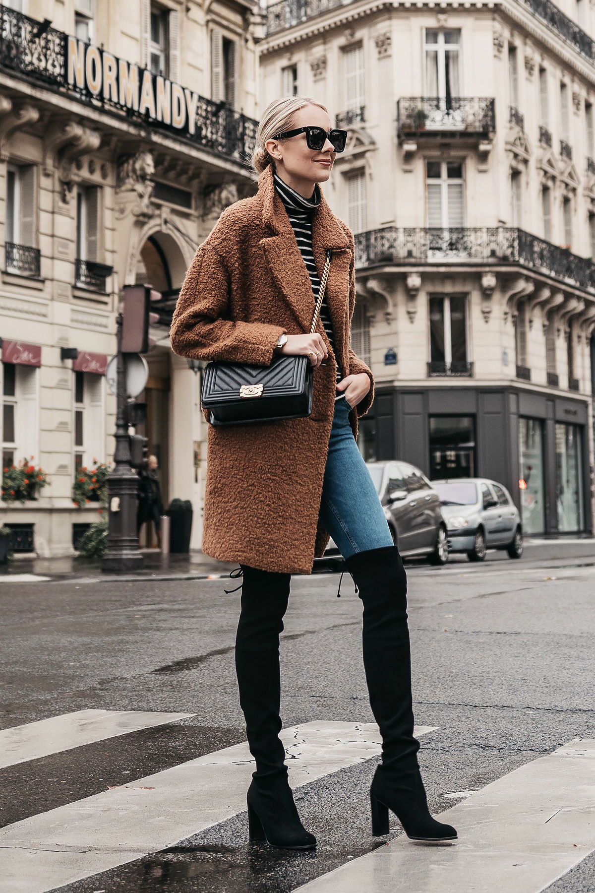 A cream teddy bear coat styled over an all-black outfit in street style