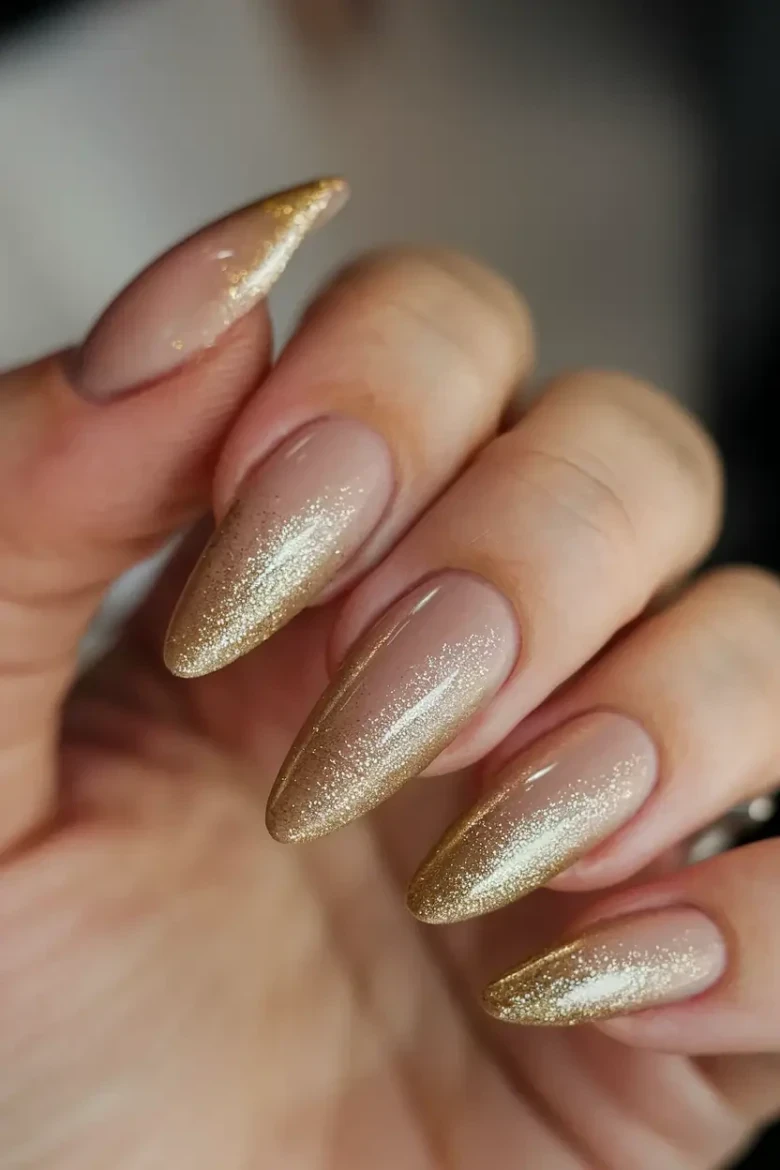 Stiletto nude nails with gold glitter gradient from the tips