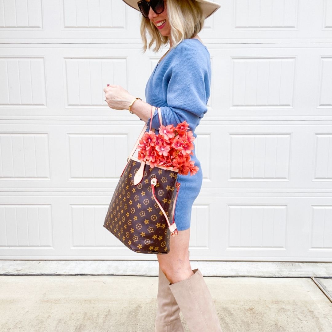 Light blue knit mini sweater dress with beige knee-high suede boots, a monogram tote filled with flowers, a wide-brim hat and sunglasses