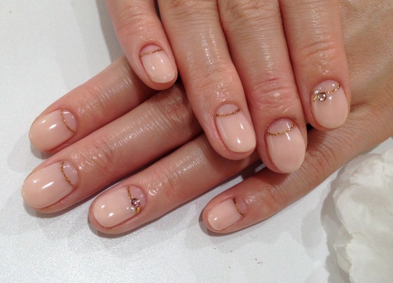 Sheer nude nails with fine gold line art near the cuticles and tiny gems