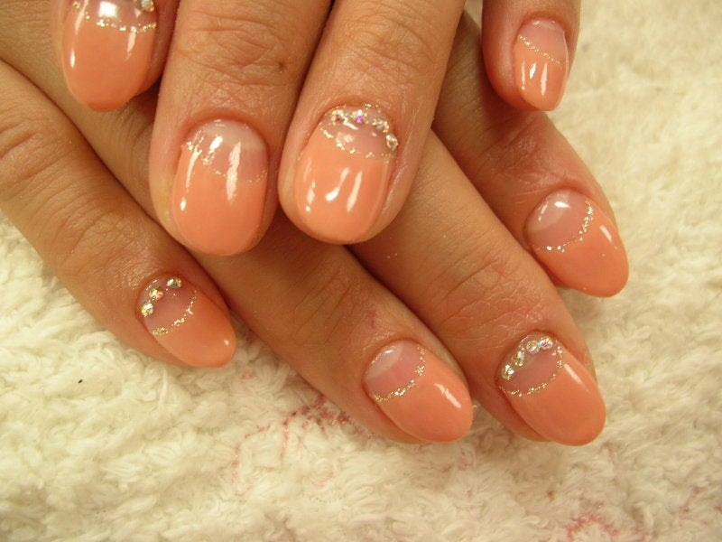 Peachy nude round nails with glitter cuticle arcs and small rhinestones