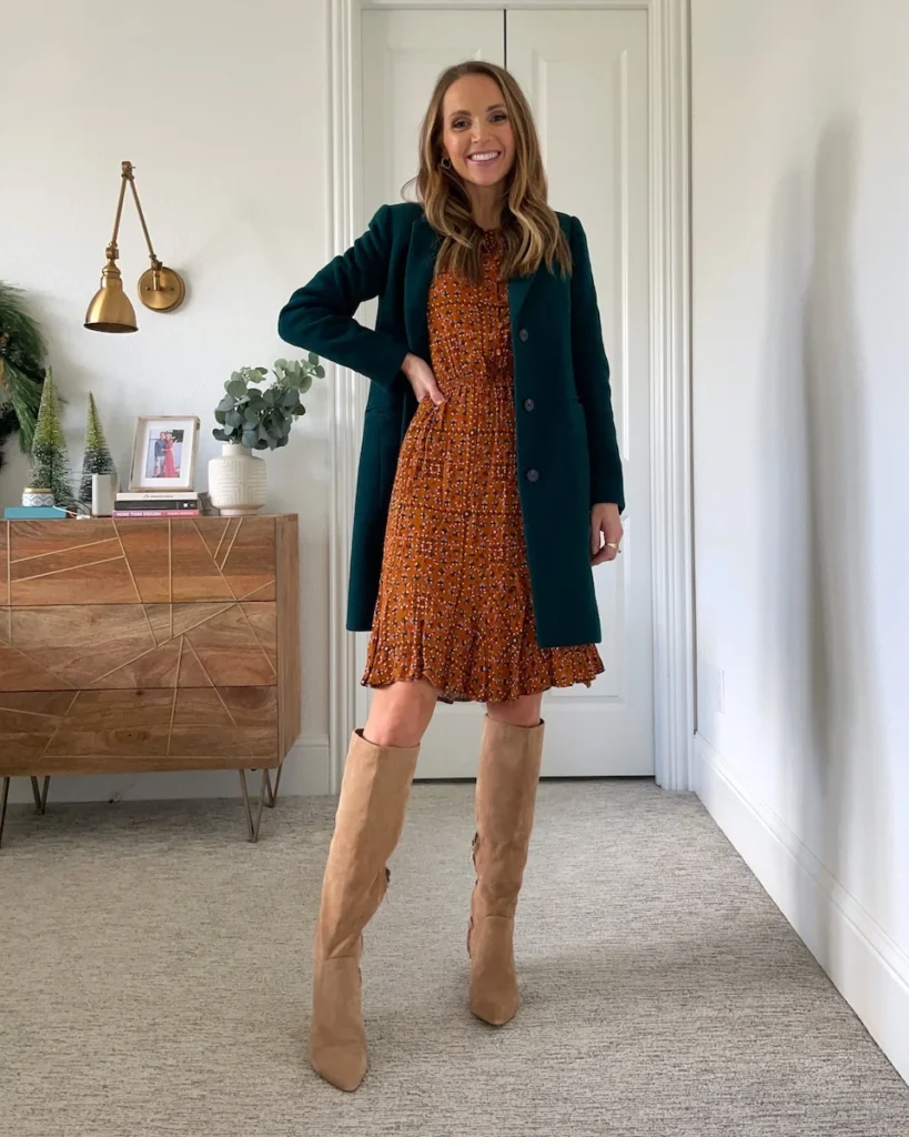 Woman wearing tan suede knee-high boots with a rust floral mini dress and dark teal wool coat