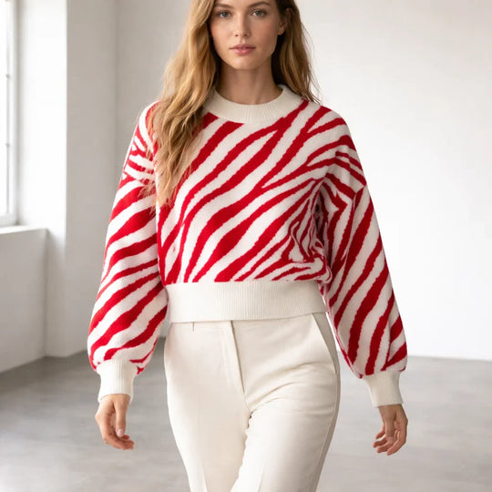 Woman wearing a red and white zebra-stripe sweater with white jeans