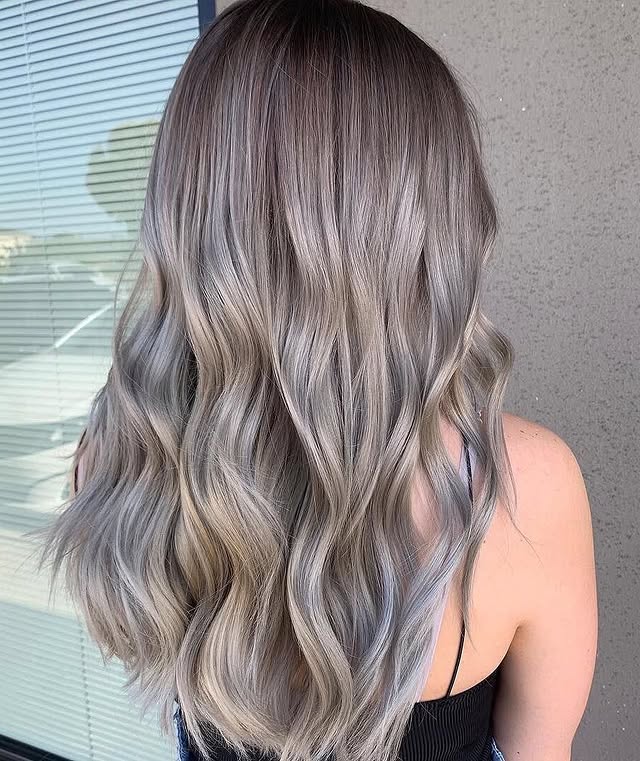 Mushroom blonde balayage with cool smoky tones and waves